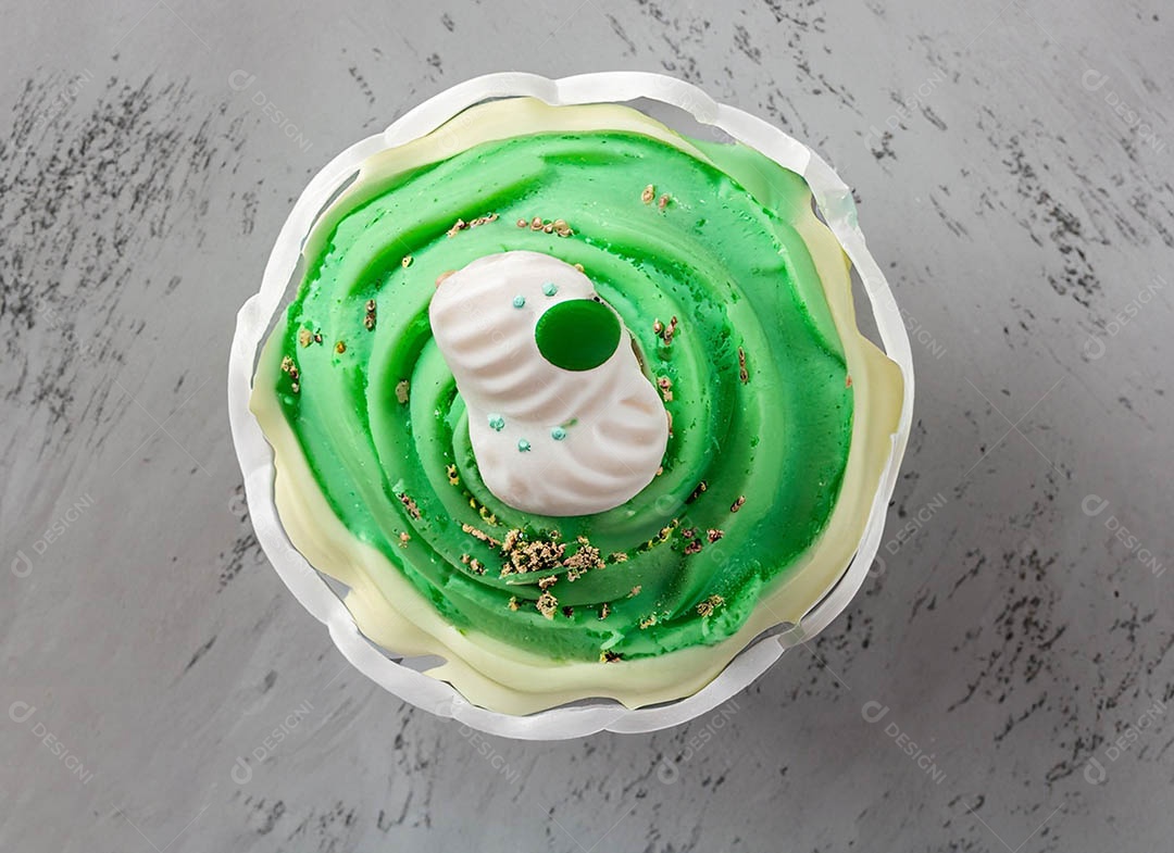 Cupcake com cobertura verde e branca sob fundo isolado