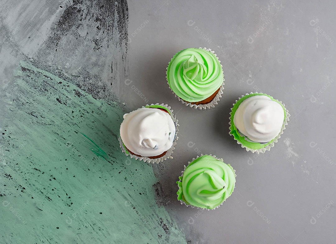 Cupcake com cobertura verde e branca sob fundo isolado