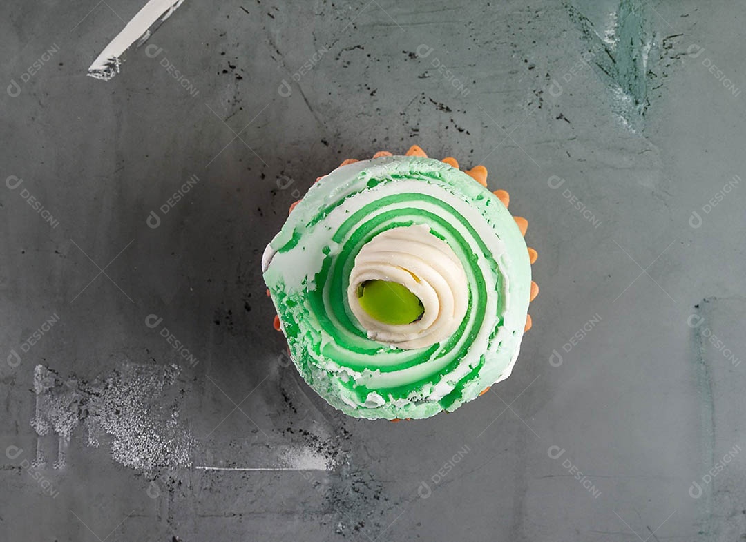 Cupcake com cobertura verde e branca sob fundo isolado