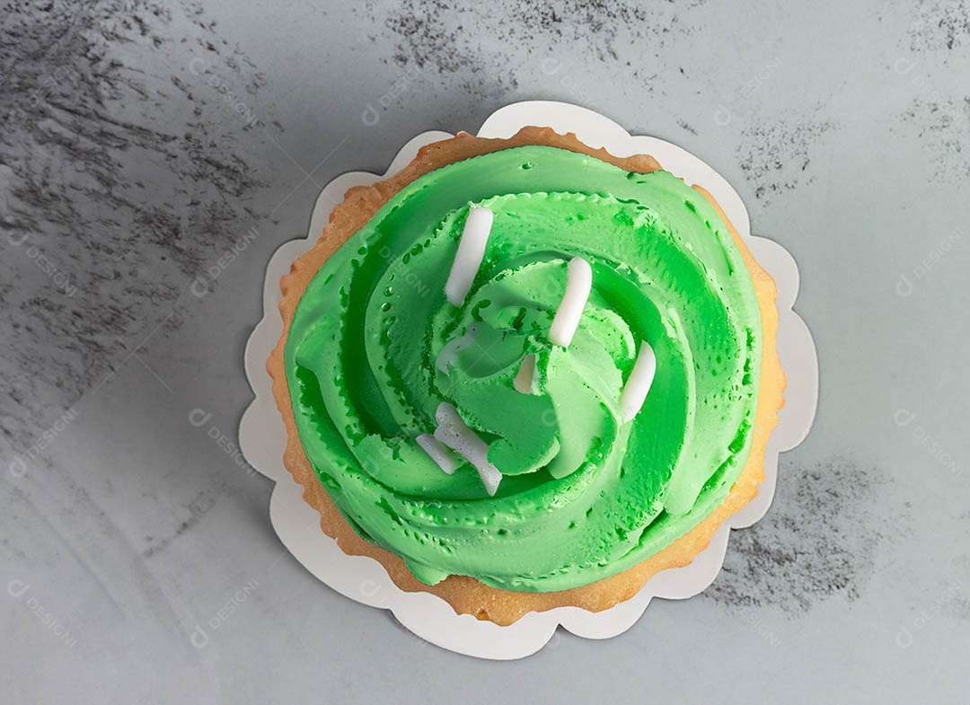 Cupcake com cobertura verde e branca sob fundo isolado