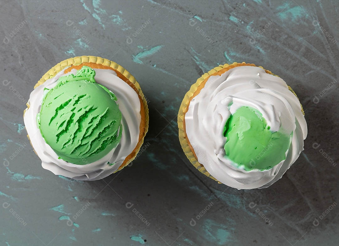 Cupcake com cobertura verde e branca sob fundo isolado