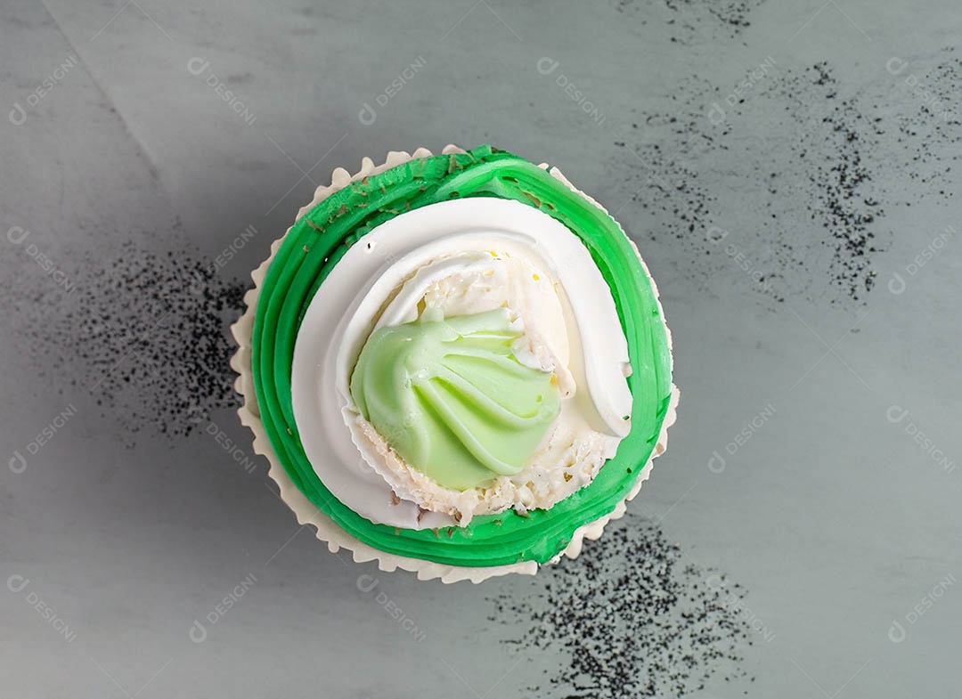 Cupcake com cobertura verde e branca sob fundo isolado