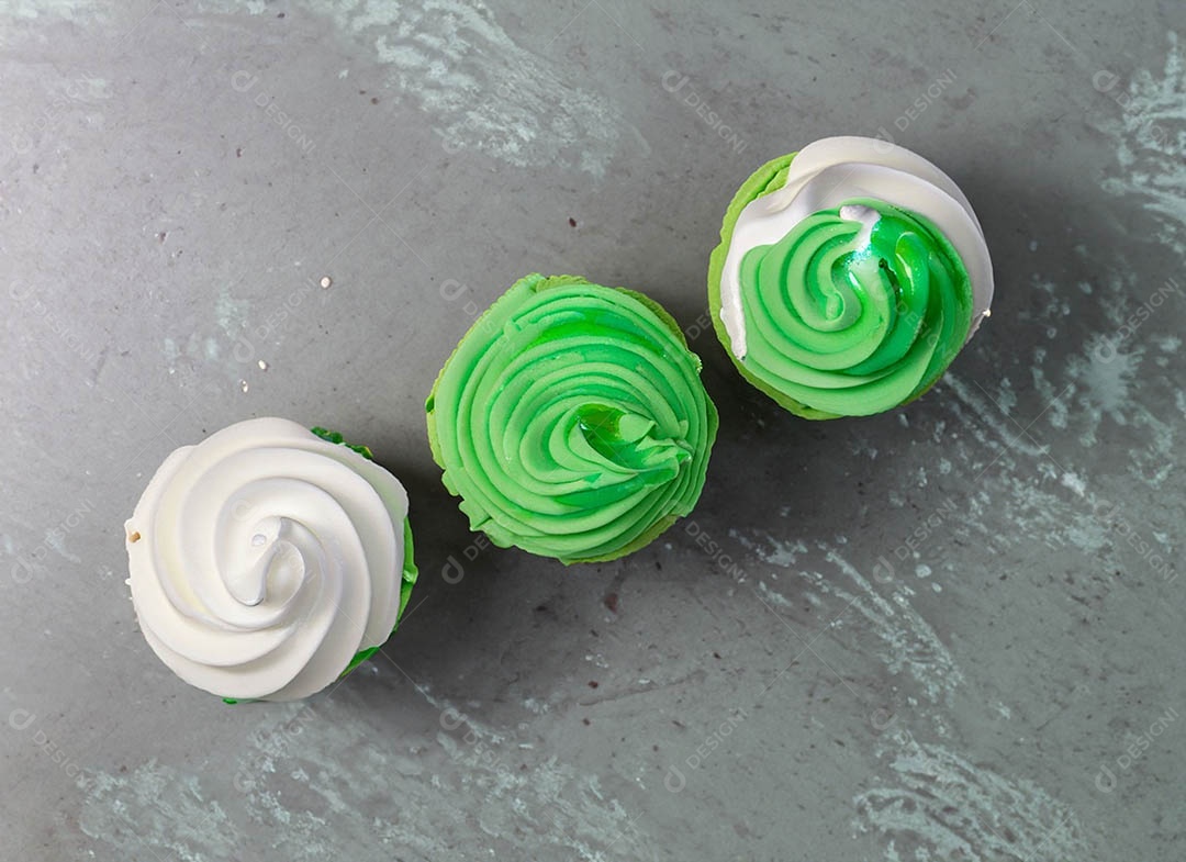 Cupcake com cobertura verde e branca sob fundo isolado