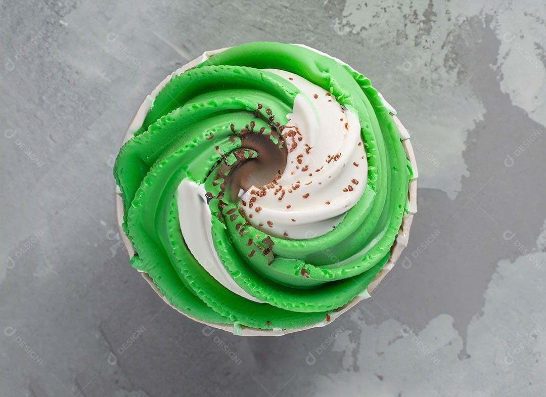 Cupcake com cobertura verde e branca sob fundo isolado
