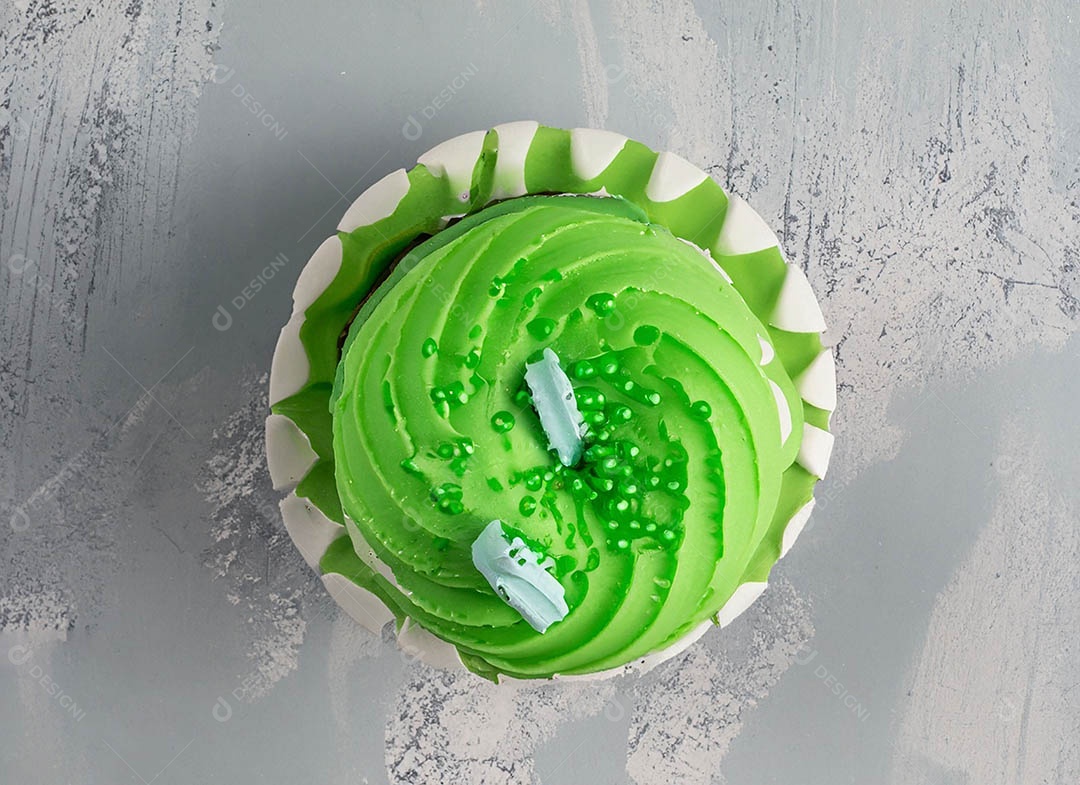 Cupcake com cobertura verde e branca sob fundo isolado