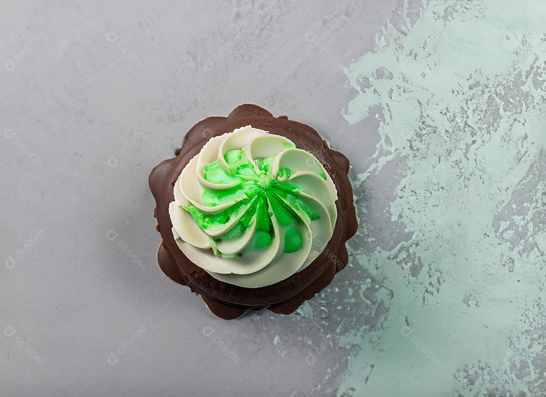 Cupcake com cobertura verde e branca sob fundo isolado