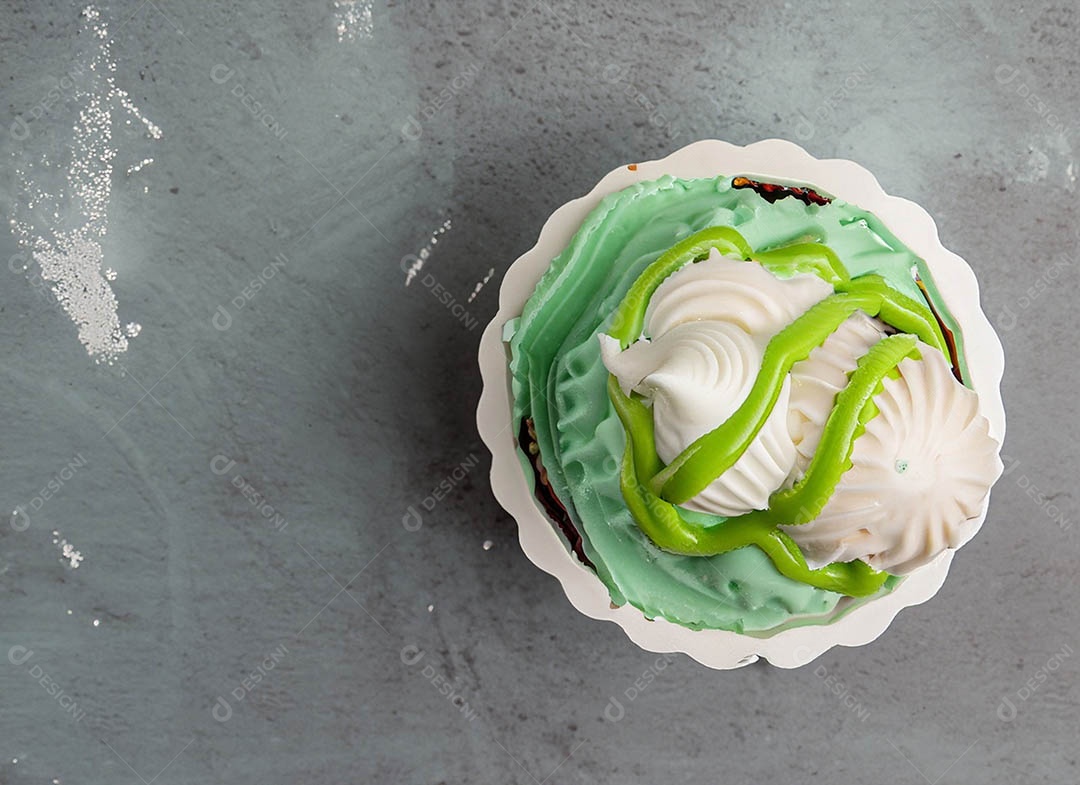 Cupcake com cobertura verde e branca sob fundo isolado