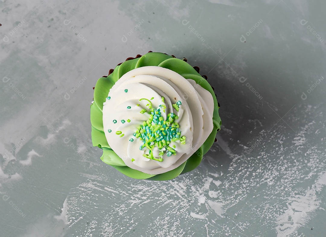 Cupcake com cobertura verde e branca sob fundo isolado