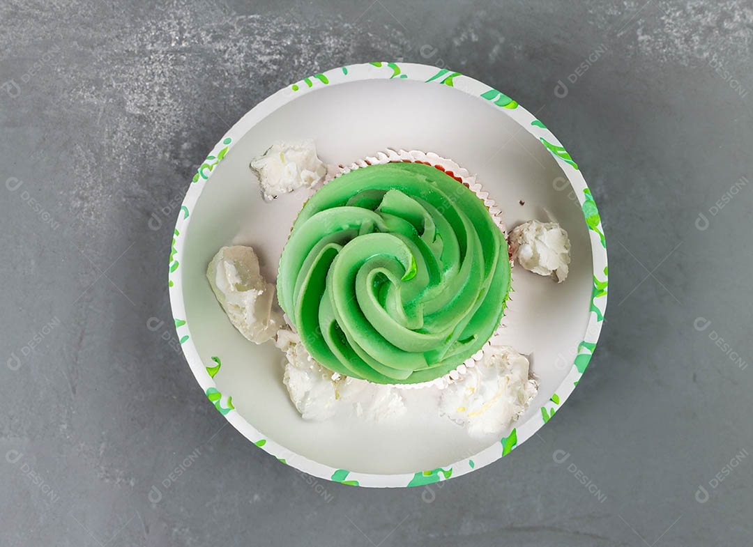 Cupcake com cobertura verde e branca sob fundo isolado