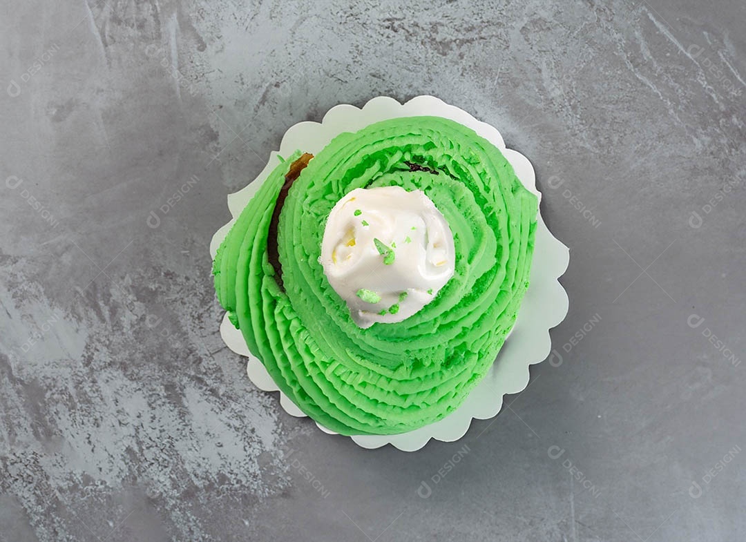 Cupcake com cobertura verde e branca sob fundo isolado