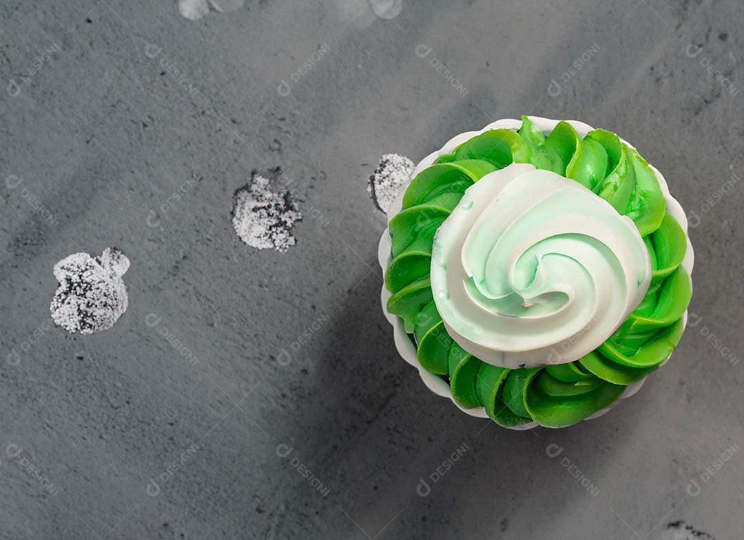 Cupcake com cobertura verde e branca sob fundo isolado