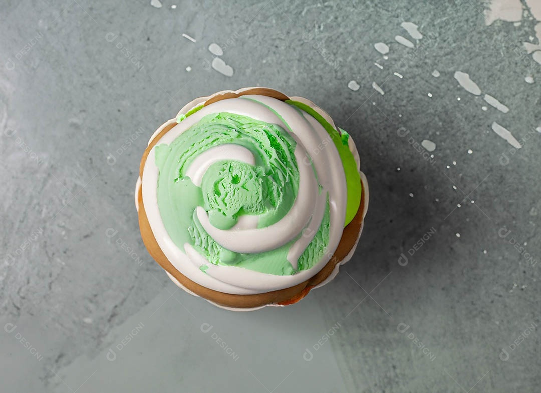 Cupcake com cobertura verde e branca sob fundo isolado