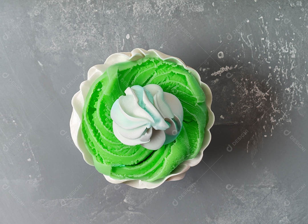 Cupcake com cobertura verde e branca sob fundo isolado