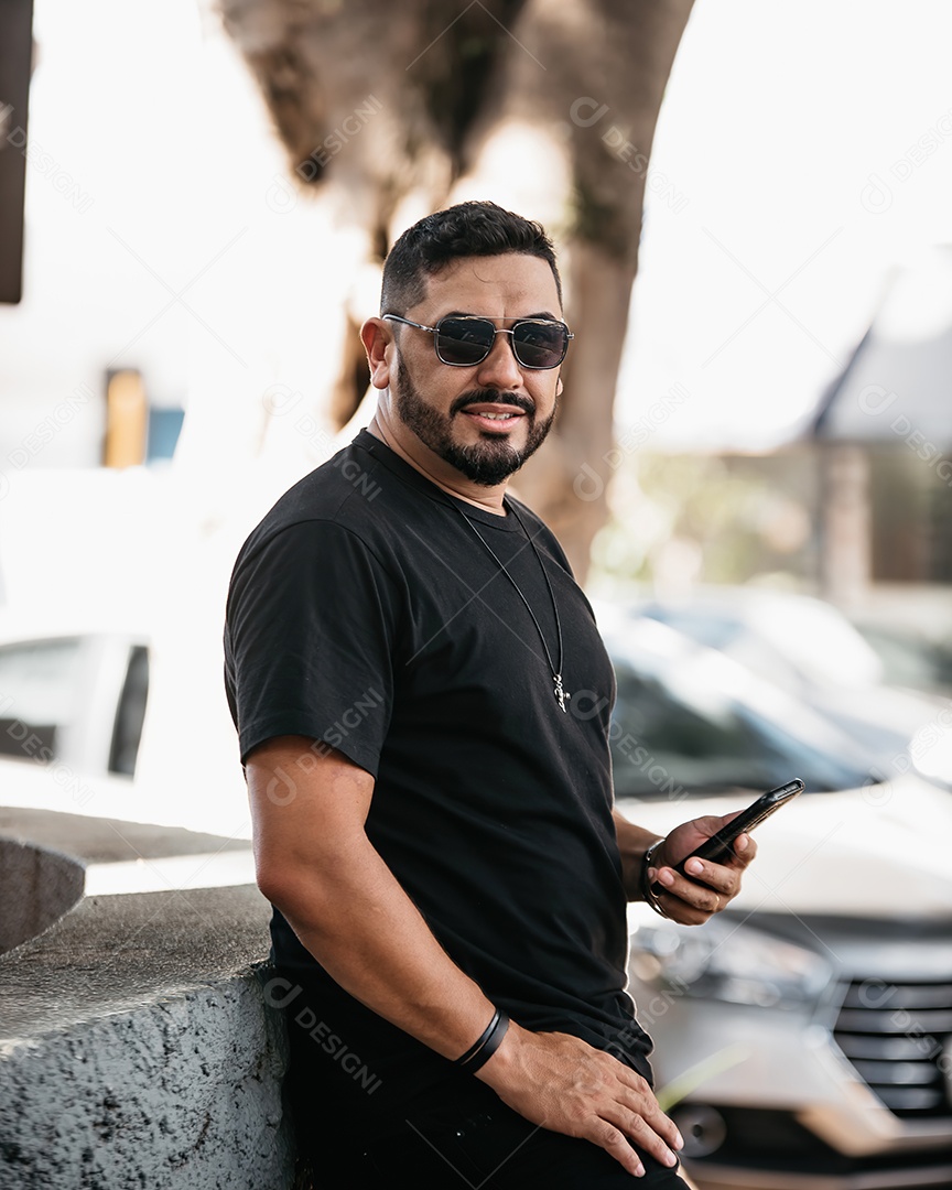 Homem lindo de meia idade sorrindo e usando óculos de sol com um celular na mão