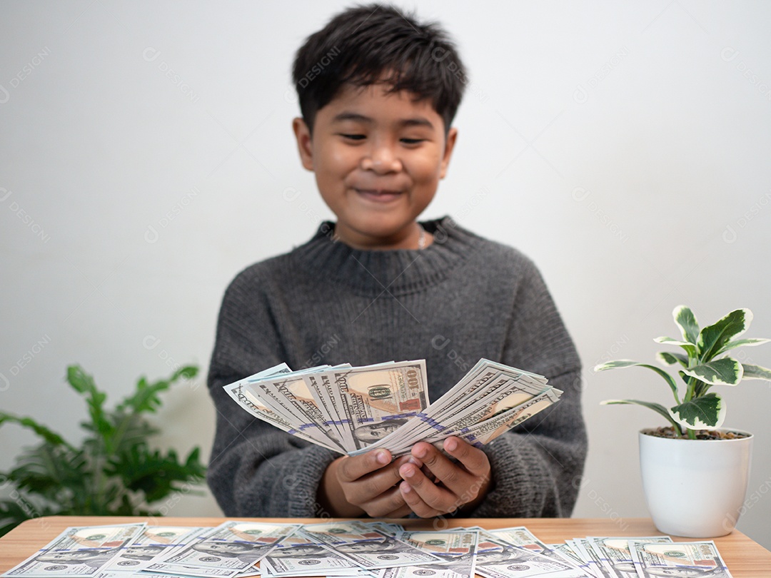 O menino segura o dinheiro com alegria. Conceito de economia de dinheiro, investimento, finanças.