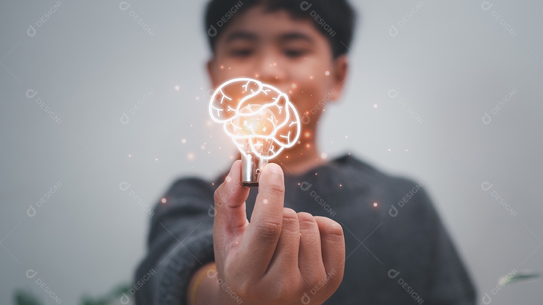 O menino está segurando uma lâmpada. Representa o conceito de educação, aprendizado, inovação e sucesso.