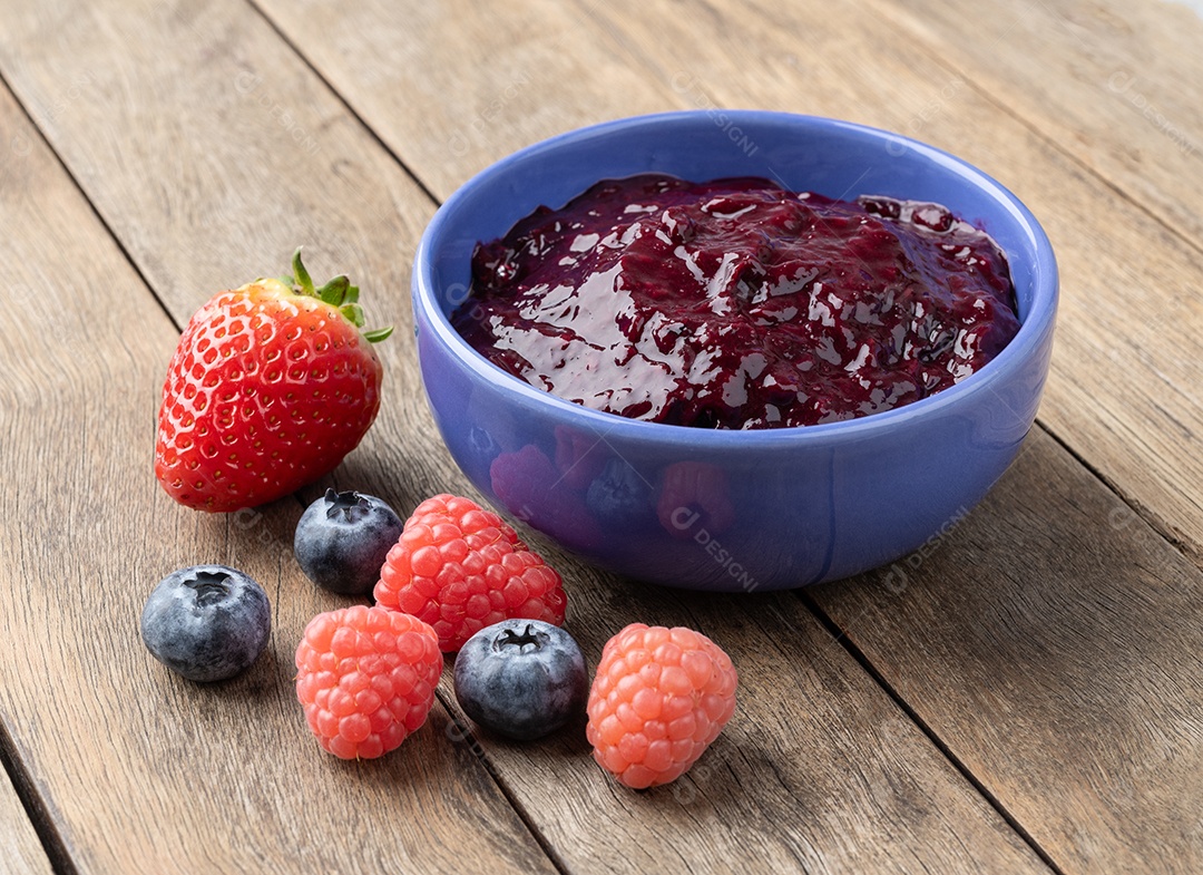 Geleia de bagas em uma tigela com frutas sobre a mesa de madeira