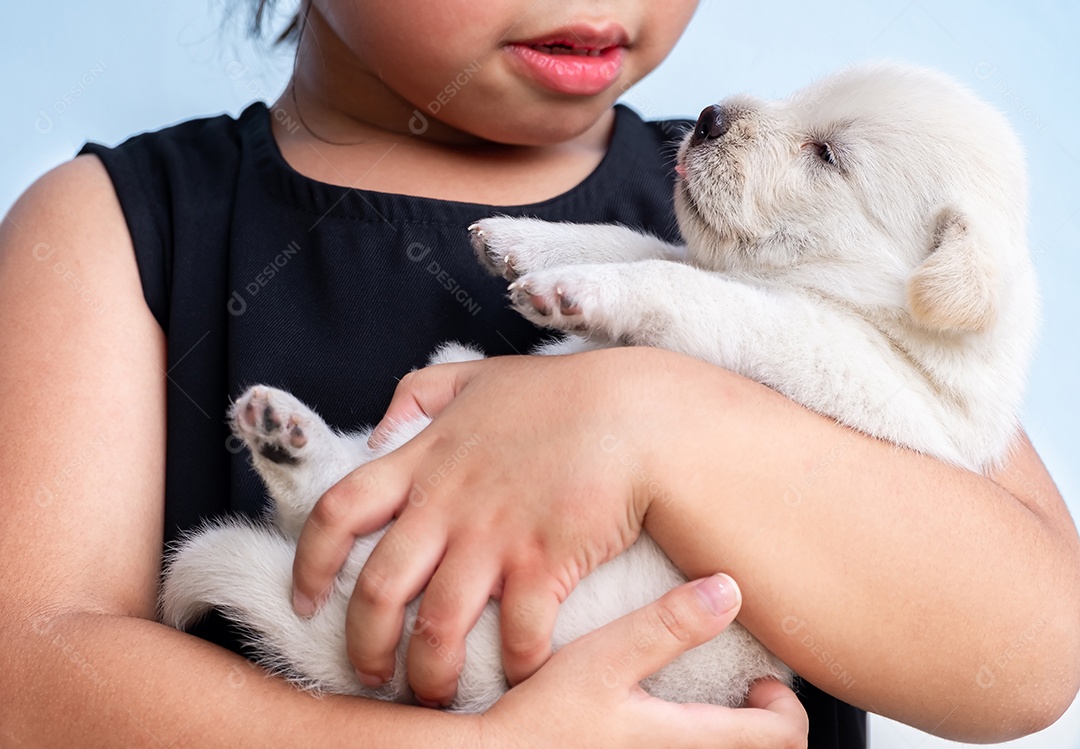 Menina de camisa preta segurando um cachorrinho marrom