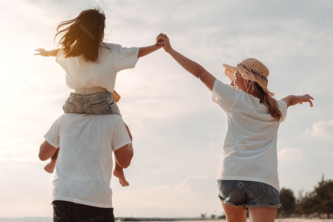 A família asiática feliz aprecia a praia do mar. pai, mãe e filha se divertindo brincando