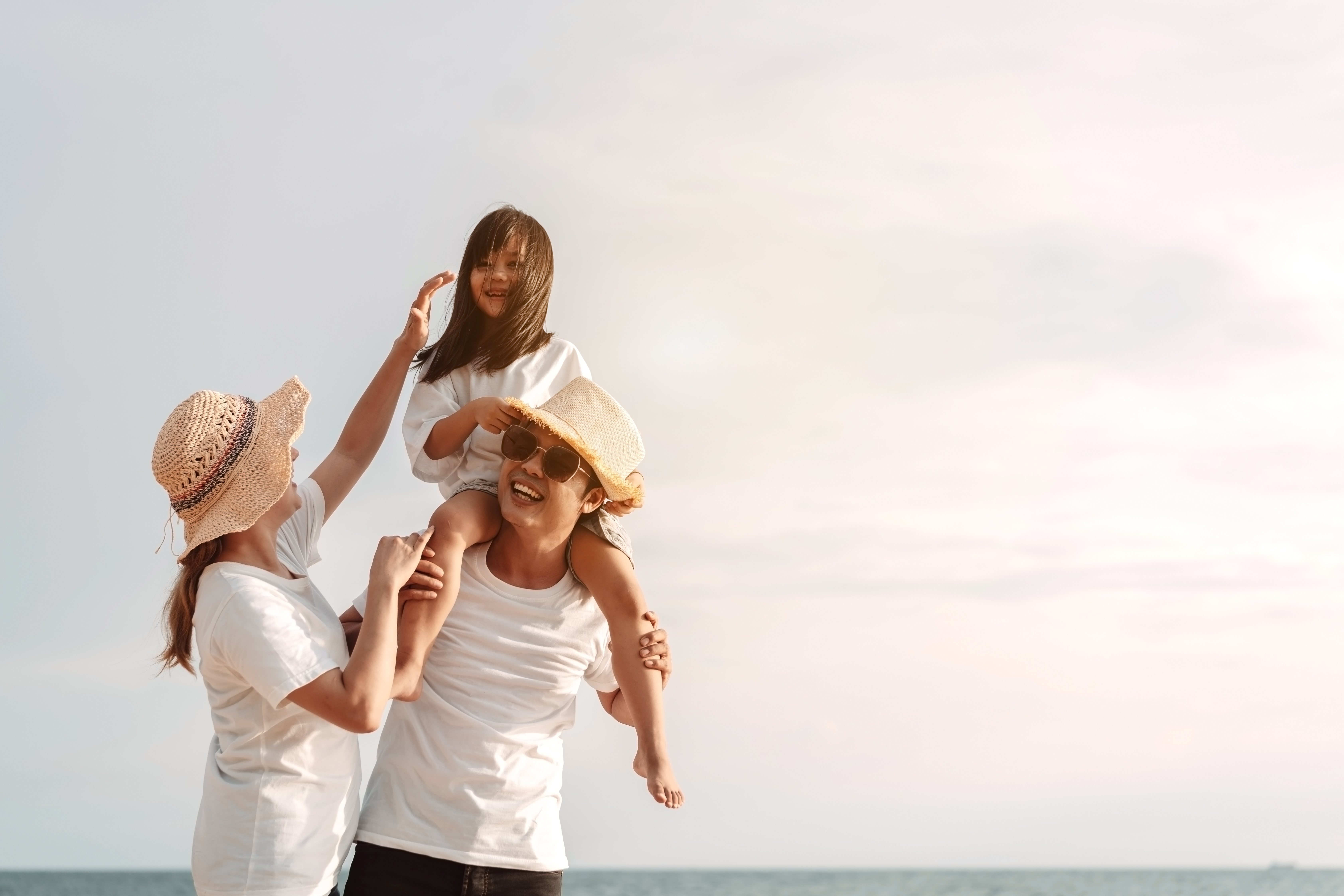 A família asiática feliz aprecia a praia do mar. pai, mãe e filha se divertindo brincando