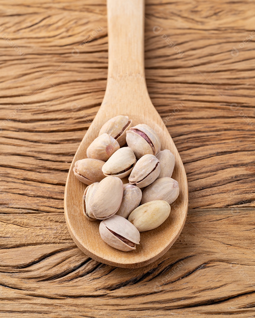 Pistache torrado salgado em uma colher sobre a mesa de madeira