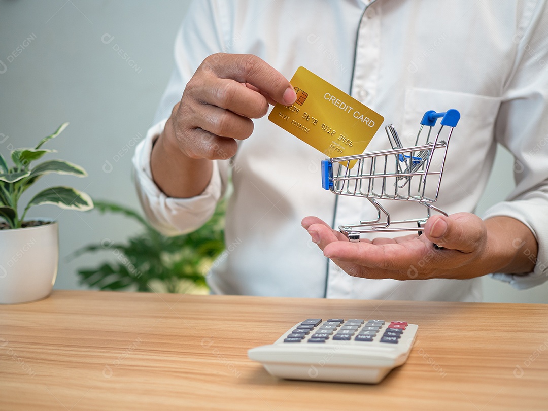 Homem segurando um cartão de crédito e pressionando uma calculadora. Conceito de compras.