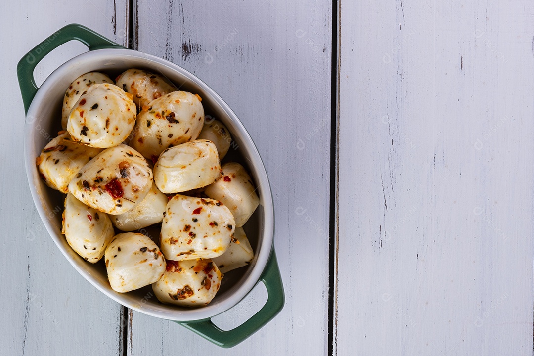 Recipiente de porcelana com bolas de mussarela de búfala temperada na mesa branca