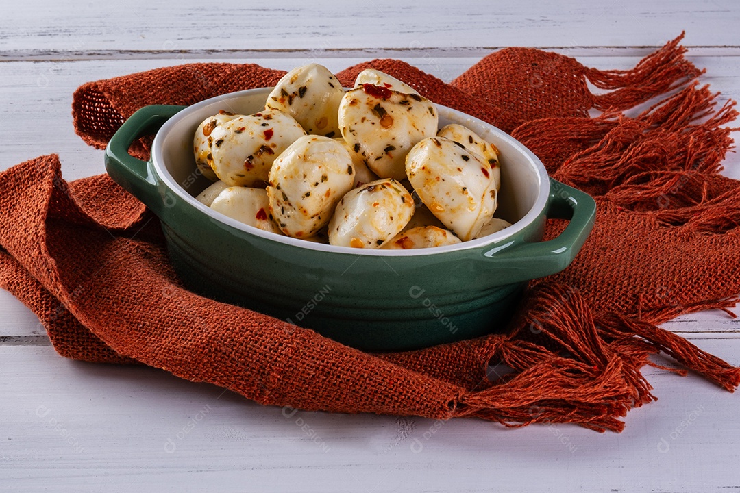 Recipiente de porcelana com bolas de mussarela de búfala temperada na mesa branca