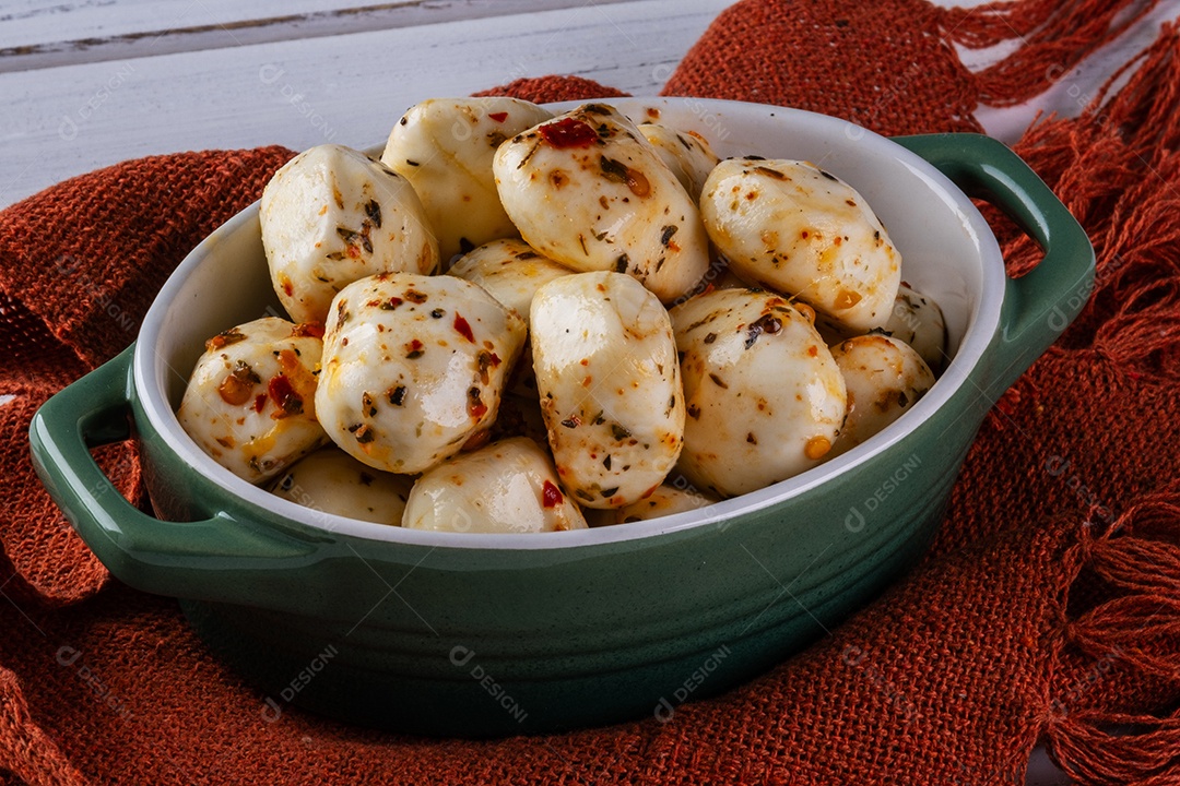 Recipiente de porcelana com bolas de mussarela de búfala temperada na mesa branca
