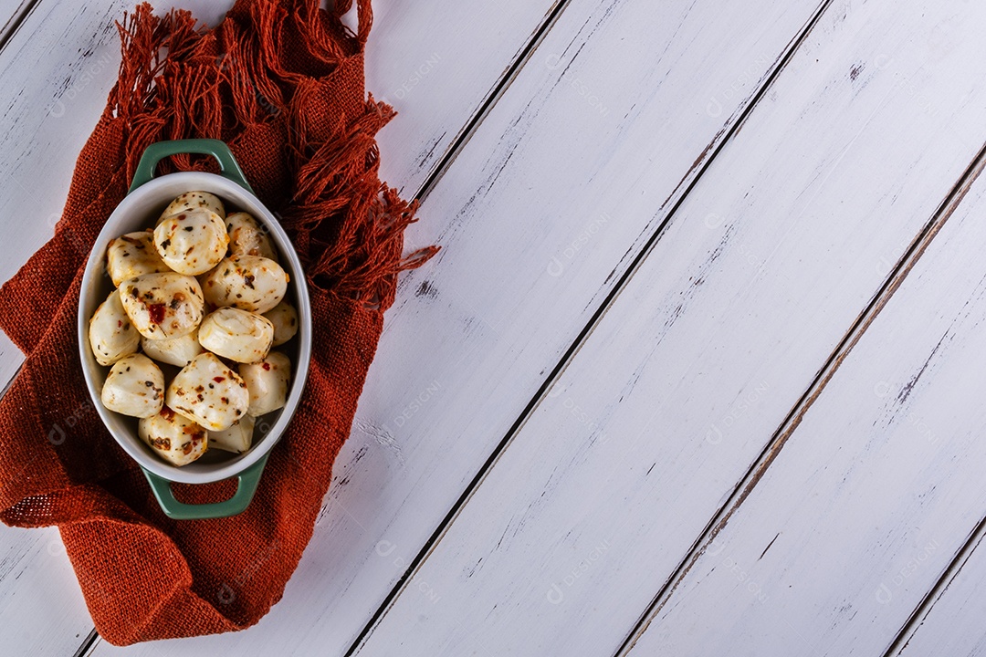 Recipiente de porcelana com bolas de mussarela de búfala temperada na mesa branca
