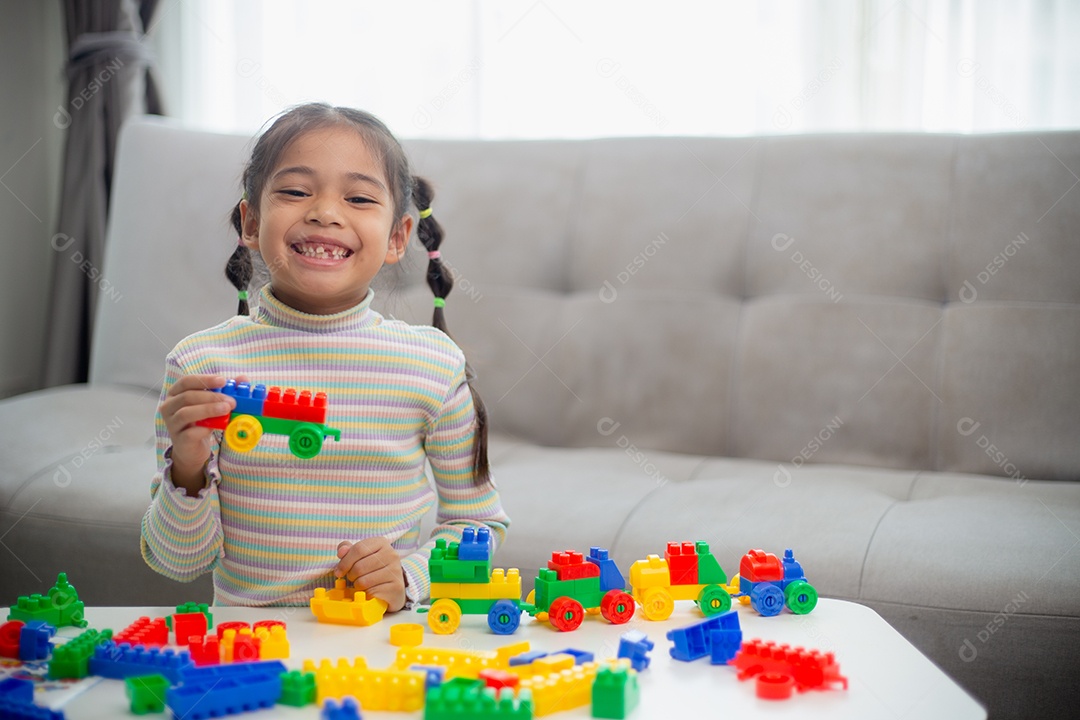 Adorável menina jogando blocos de brinquedo em uma sala iluminada