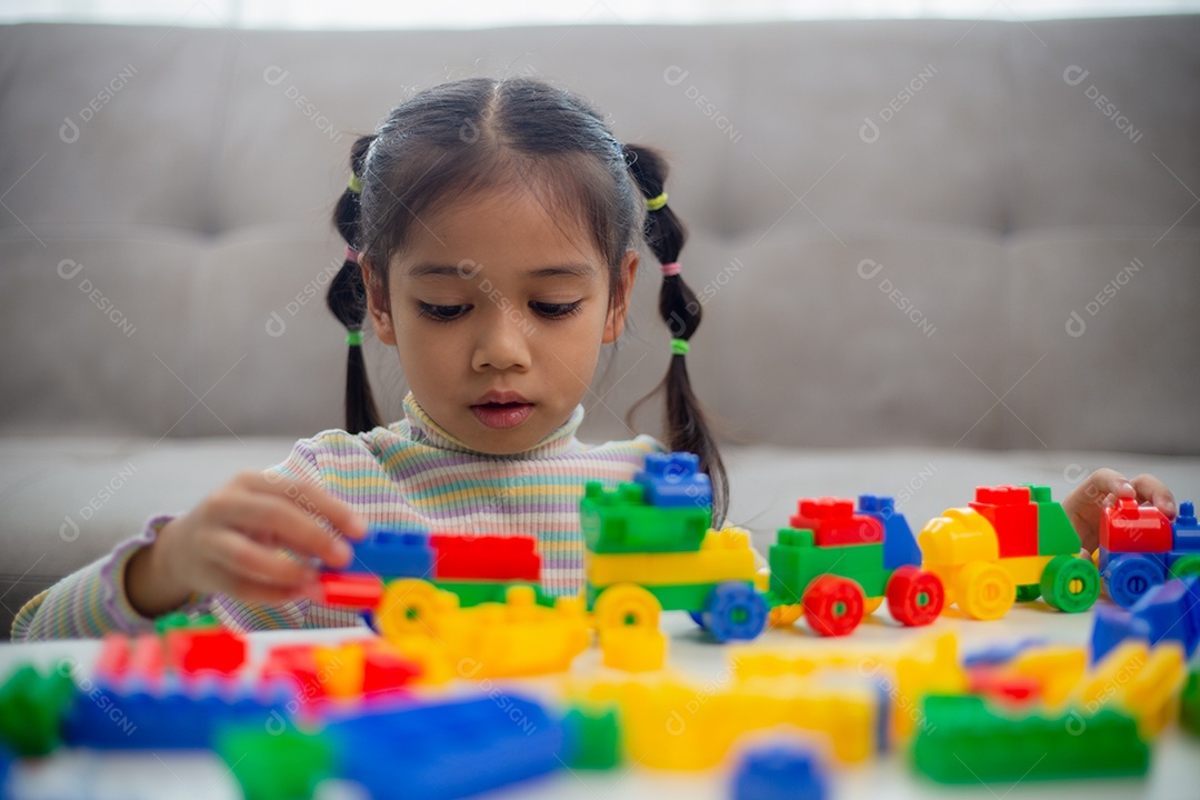 Adorável menina jogando blocos de brinquedo em uma sala iluminada