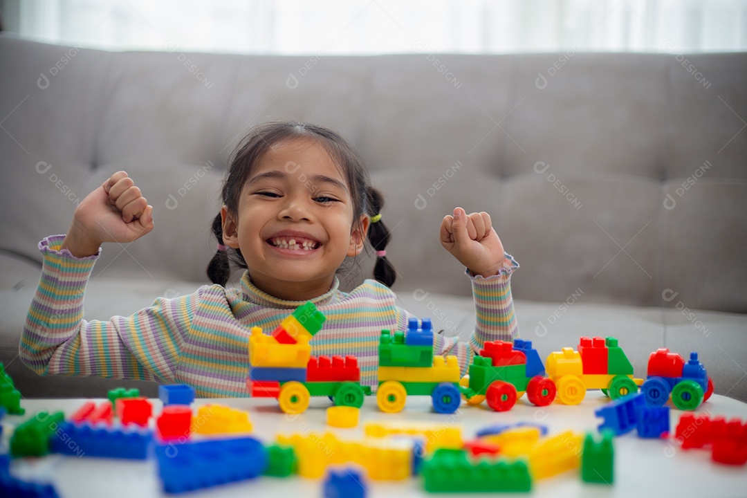 Adorável menina jogando blocos de brinquedo em uma sala iluminada