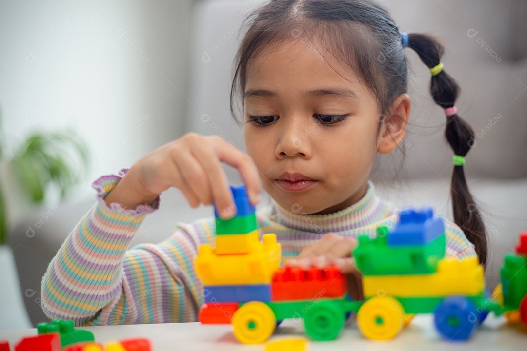 Adorável menina jogando blocos de brinquedo em uma sala iluminada