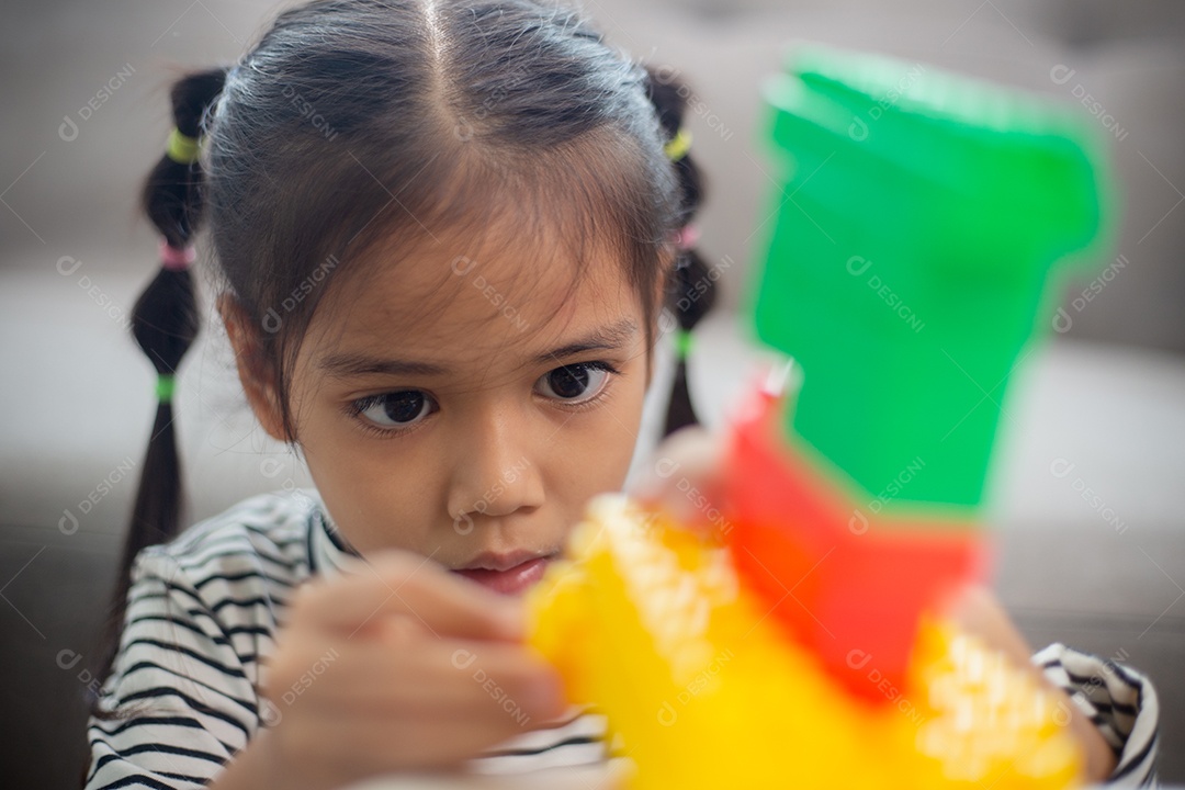 Adorável menina jogando blocos de brinquedo em uma sala iluminada