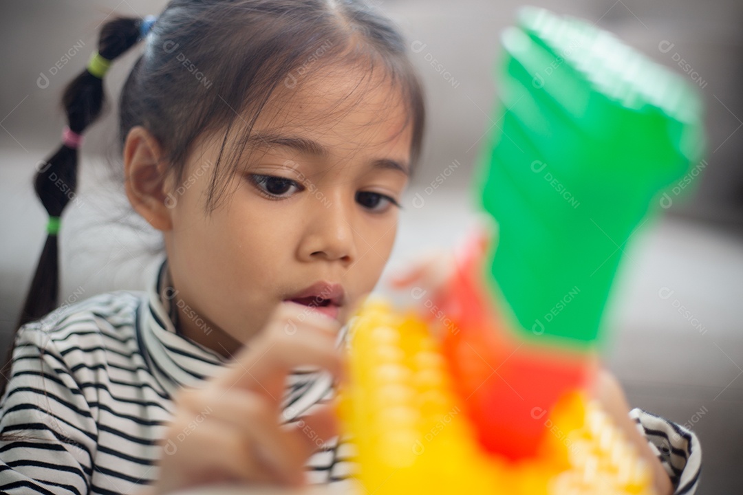 Adorável menina jogando blocos de brinquedo em uma sala iluminada