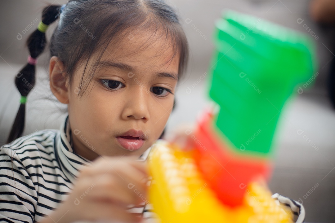 Adorável menina jogando blocos de brinquedo em uma sala iluminada