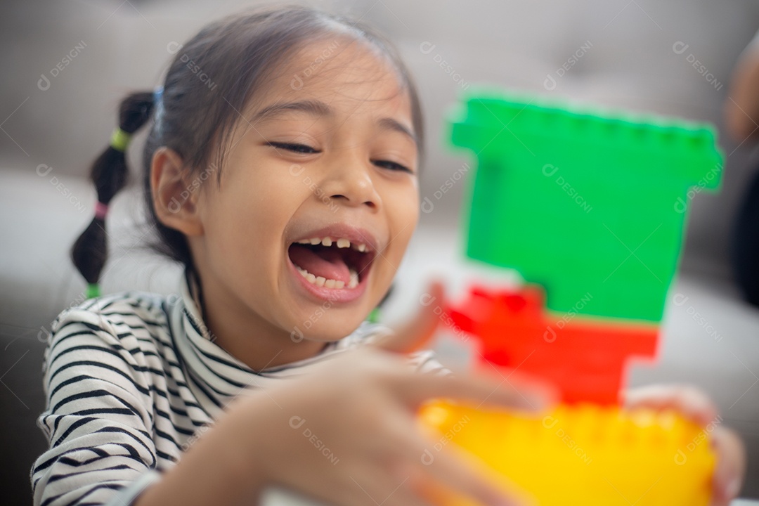 Adorável menina jogando blocos de brinquedo em uma sala iluminada