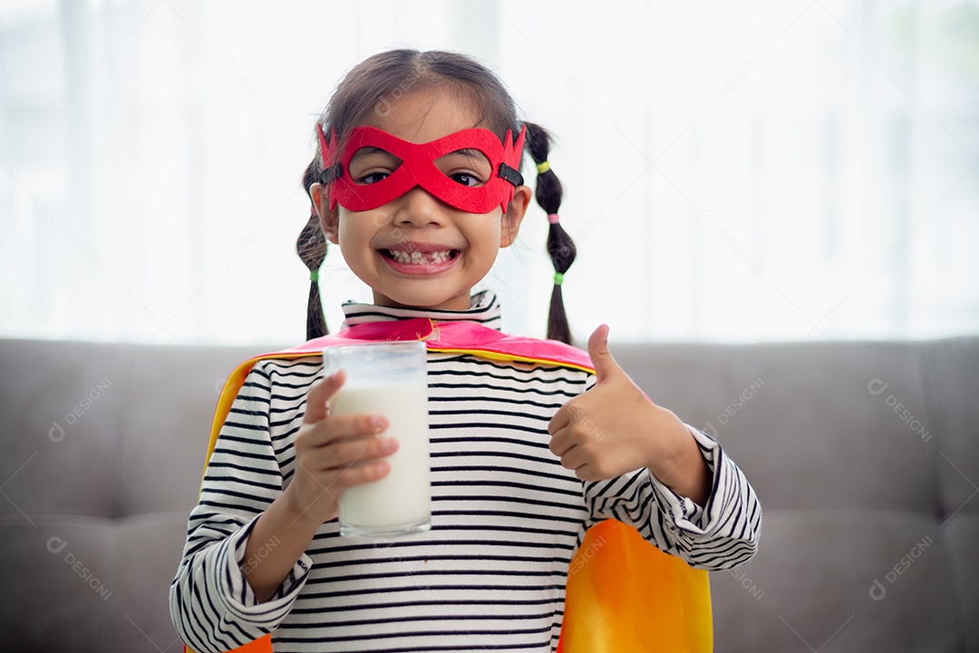 Criança bonitinha asiática segurando um copo de leite em casa. sinta-se feliz e goste de beber leit