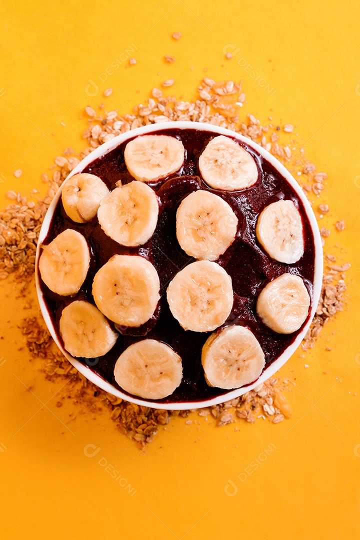 Tigela com delicioso açaí e banana em fundo amarelo