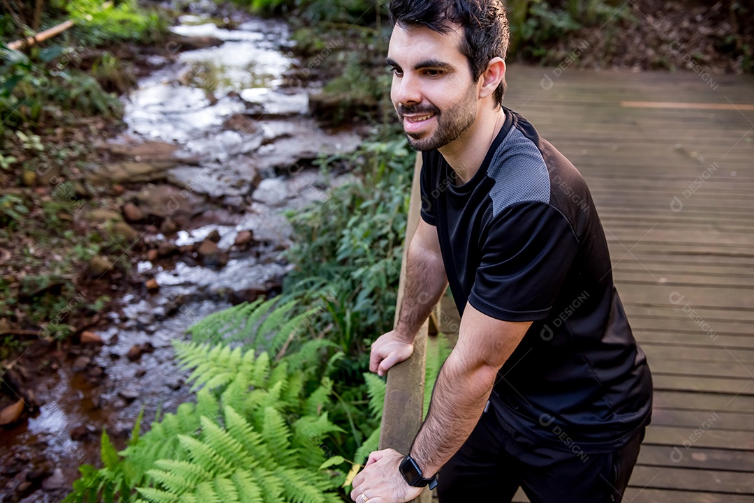 Um homem feliz observando uma nascente de água em uma floresta na Mata Atlântica no Brasil