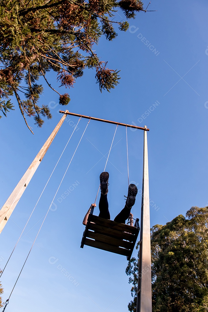Garota em balanço gigante, céu azul ao fundo