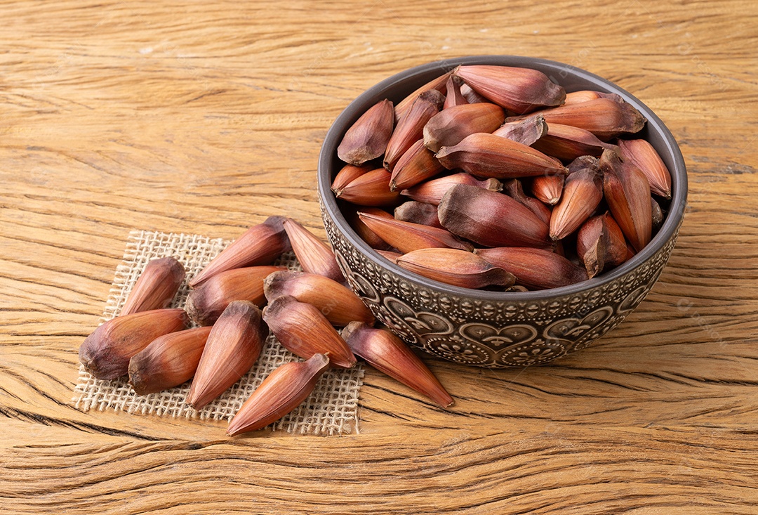 Pinhões ou sementes de pinheiro em uma tigela sobre a mesa de madeira