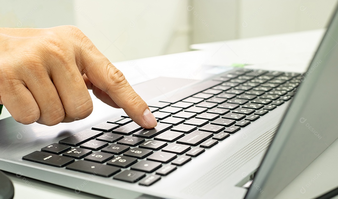 dedo humano pressionando a tecla Enter no teclado do laptop, confirmando o processo de operação do sistema de computador