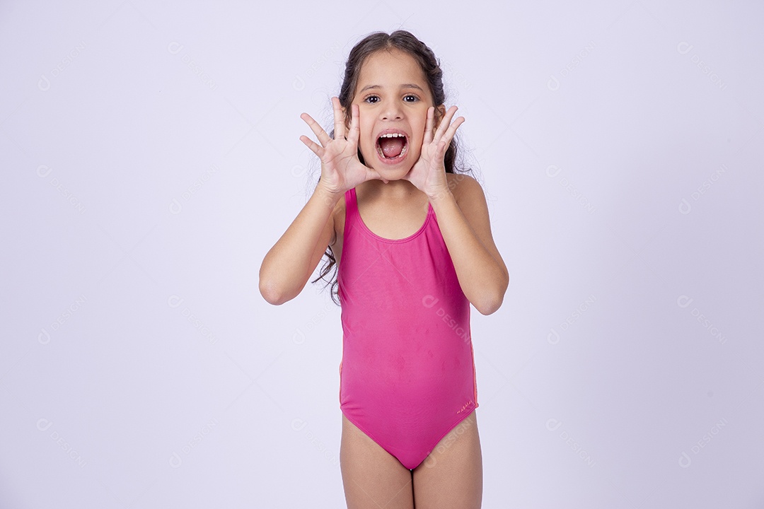 Linda garotinha sorridente com maiô segurando frasco de protetor solar