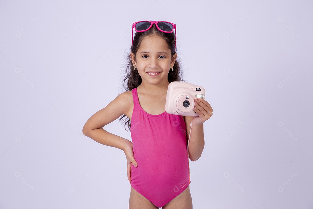 Linda garotinha sorridente com óculos de sol e maiô rosa