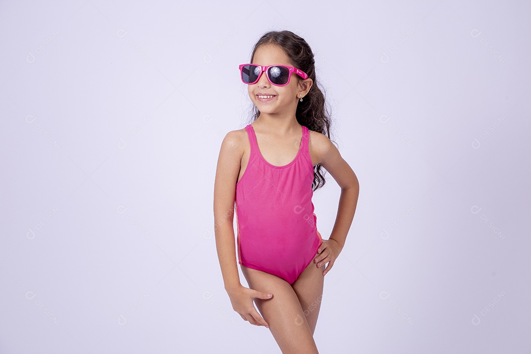 Linda garotinha sorridente com óculos de sol e maiô