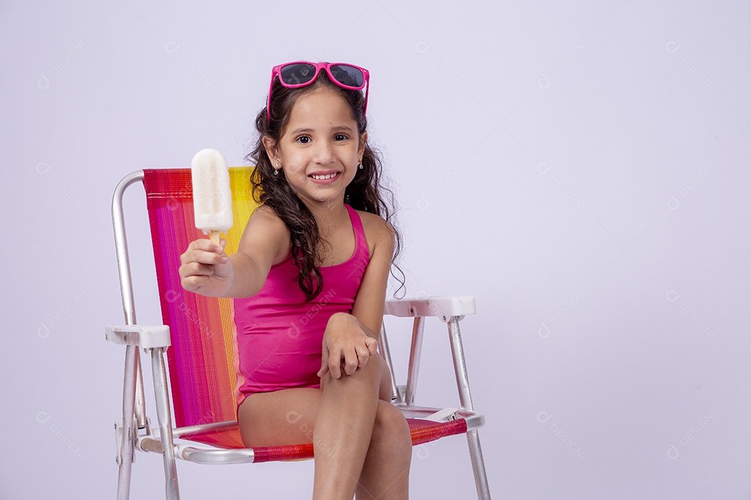 Linda garotinha sorridente com óculos de sol e maiô sentada na cadeira de praia
