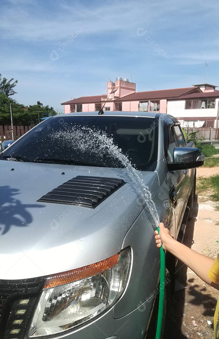 Mão com mangueira verde lavando o carro