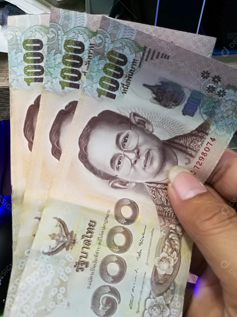 Mão segurando notas tailandesas de dinheiro